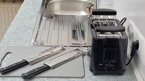Een keuken met een spoelbak, een broodrooster, een magnetron en een waterkoker.