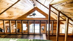 Ein geräumiges Schlafzimmer im Dachgeschoss mit Holzbalken, schräg versiegelter Decke und einem Oberlicht.