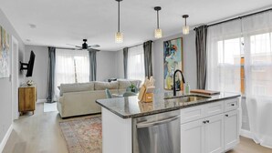 A modern kitchen with a central island, white cabinetry, and a built-in dishwasher. - Luxury Apartment In Lakewood (Lakewood)