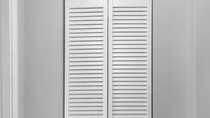 A closed white closet with horizontal slats, white trim, and a wooden floor. - Luxury Apartment In Lakewood (Lakewood)