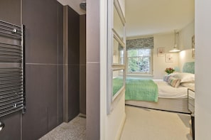 Relax in this stylish room with a large mirror, a comfortable bed, and a window offering a view of the outdoors.