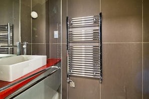 Bathroom features a sleek towel rack, a rectangular sink, and a glass shower enclosure.