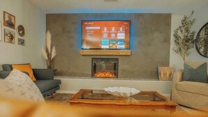 A living room with a flat-screen TV mounted above a fireplace, a sofa, and a coffee table.