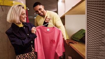 Two people in a clothing store examining a pink shirt.