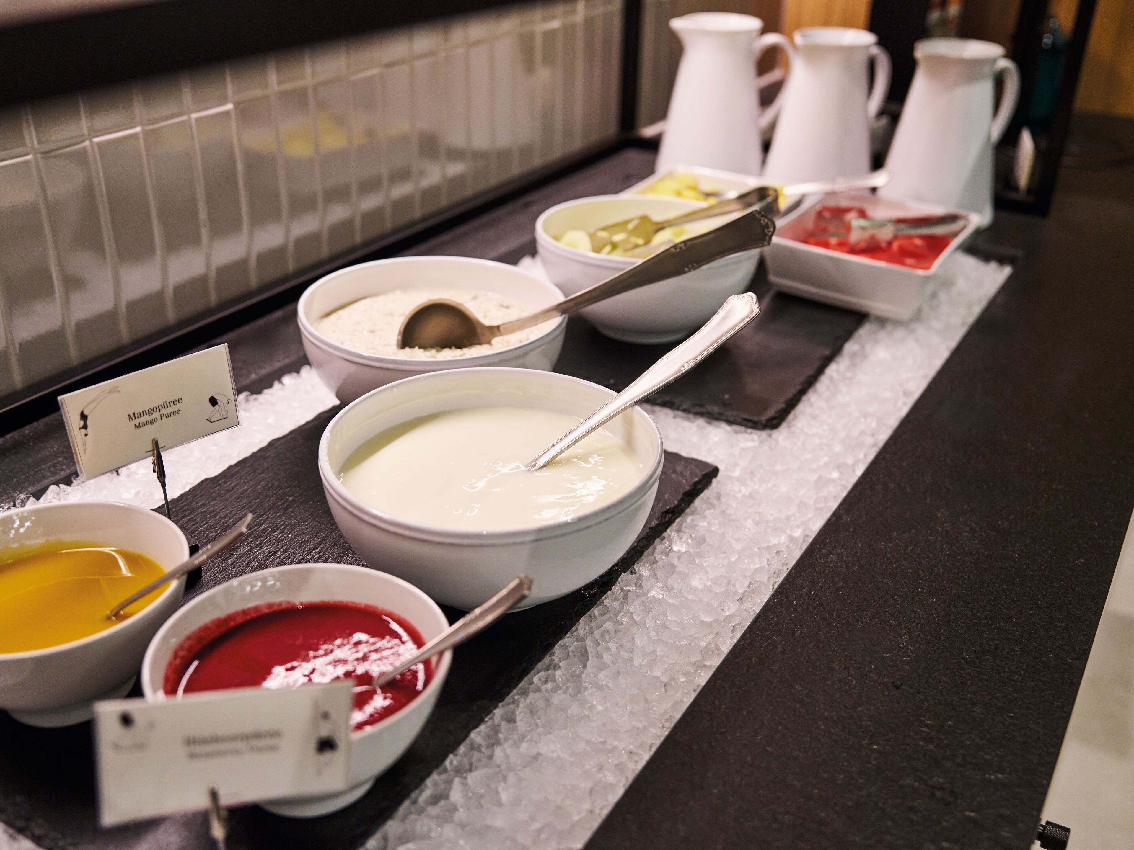Un bufé con diversos platos, incluyendo un bol de sopa blanca, un bol de sopa roja y un bol de sopa amarilla.