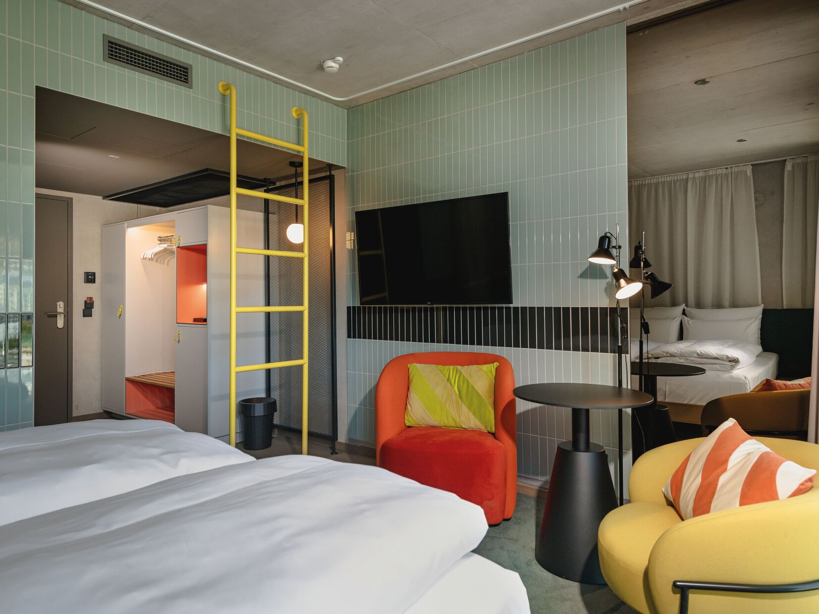 A hotel room with a bed, a chair, a desk, and a TV.