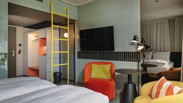 A hotel room with a bed, a chair, a desk, and a TV.