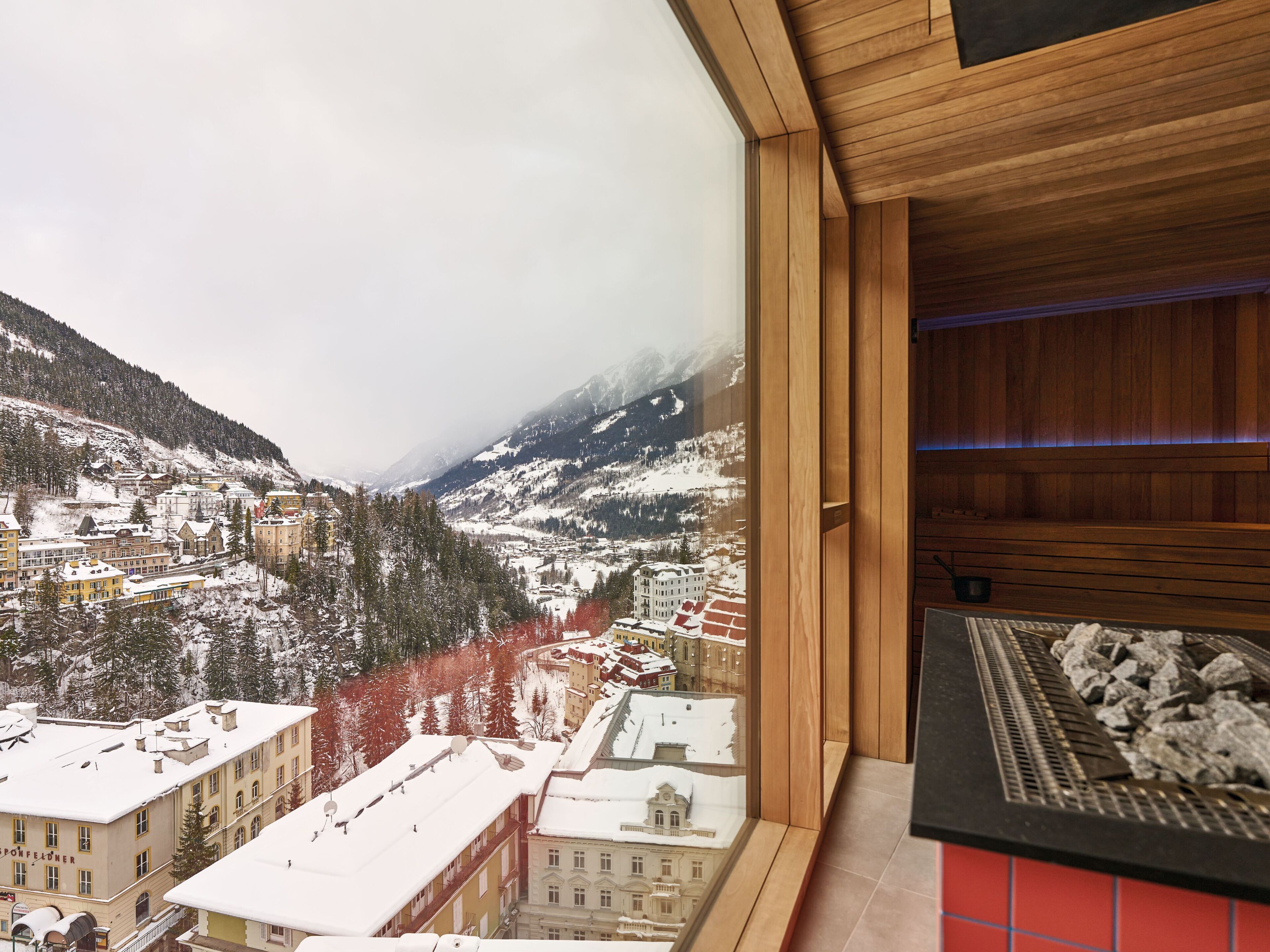 A hotel room with a large window overlooking a snowy mountain town.
