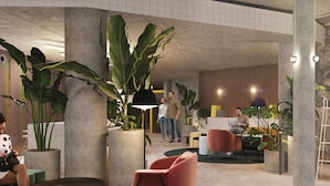 Un vestíbulo moderno con grandes plantas en macetas, asientos cómodos y una zona de recepción.