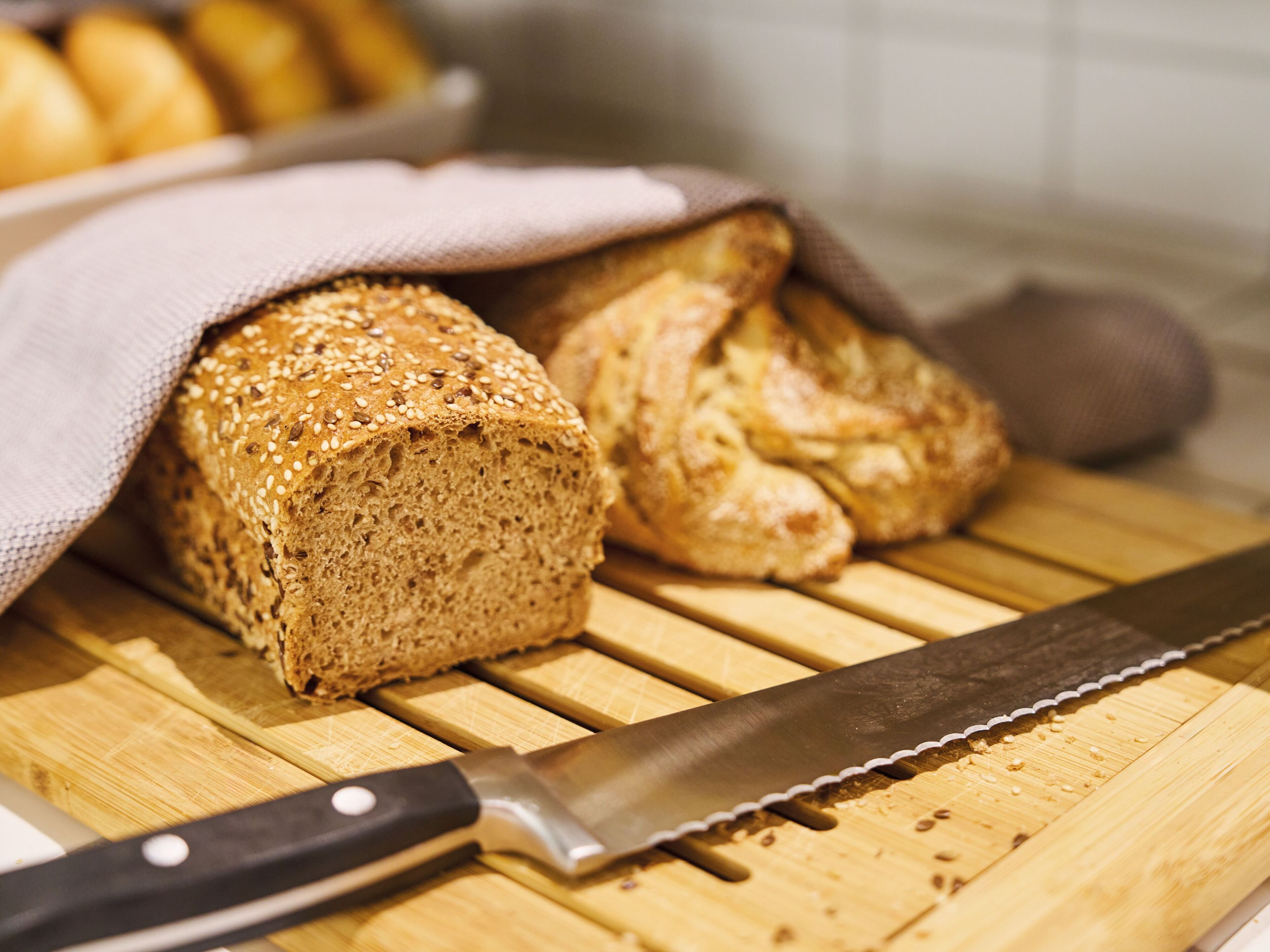 A loaf of bread and a knife on a wooden cutting board.