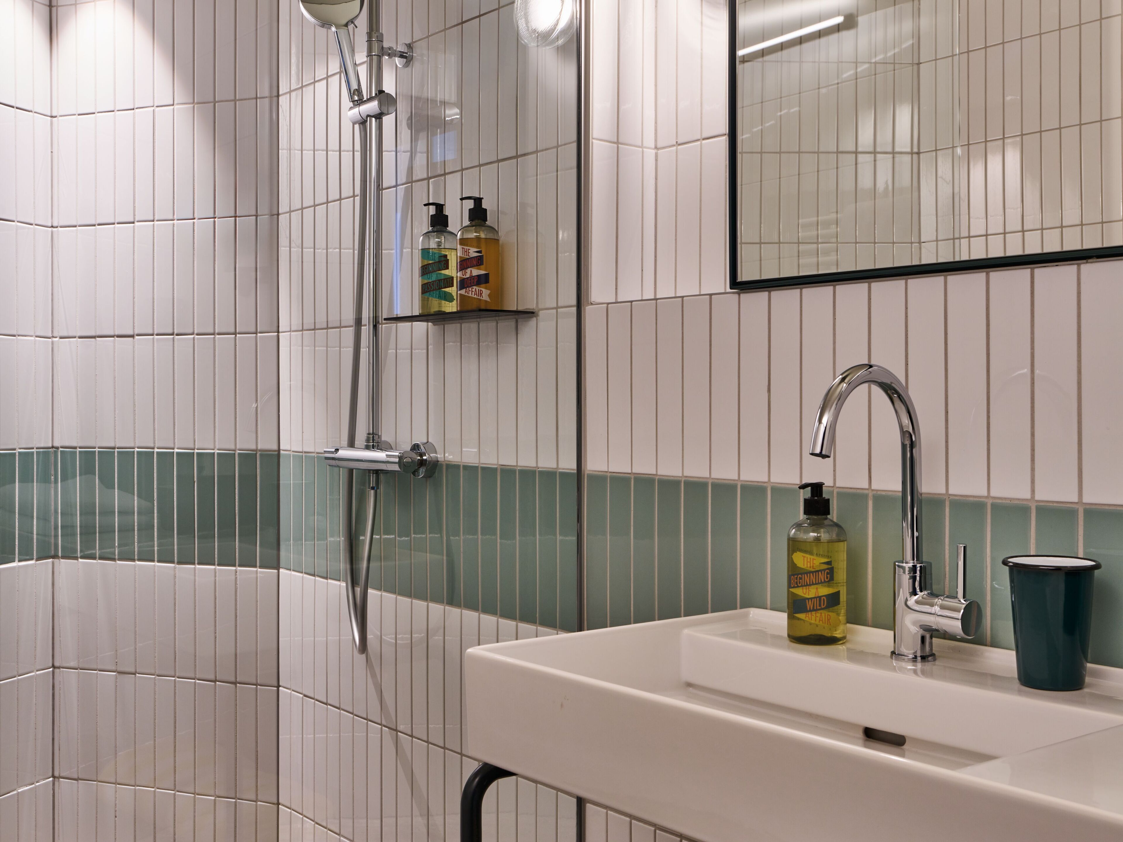 A bathroom with a bathtub, a sink with a faucet, and two bottles of shampoo on a shelf.