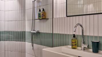A bathroom with a bathtub, a sink with a faucet, and two bottles of shampoo on a shelf.