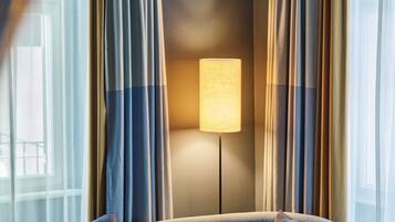 Una habitación con cama, cortinas y una lámpara de pie.