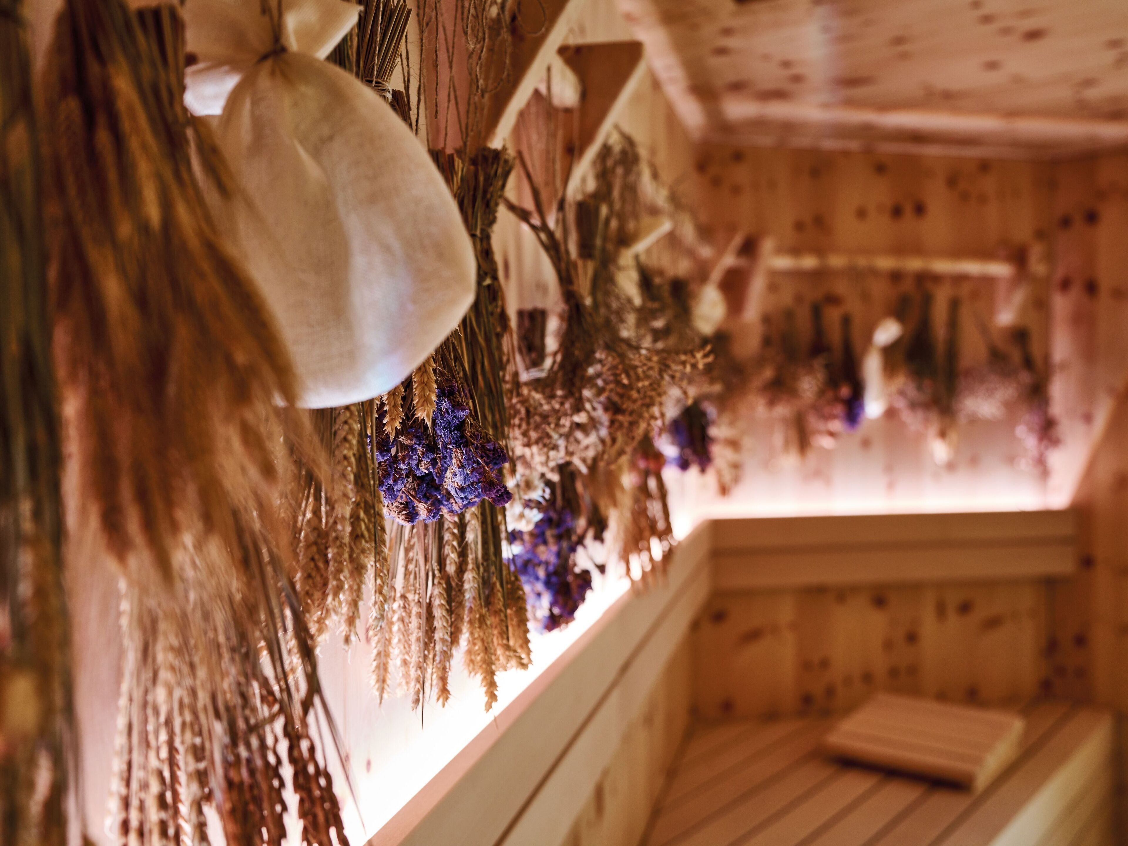 A room with wooden walls and a window with dried flowers and wheat.