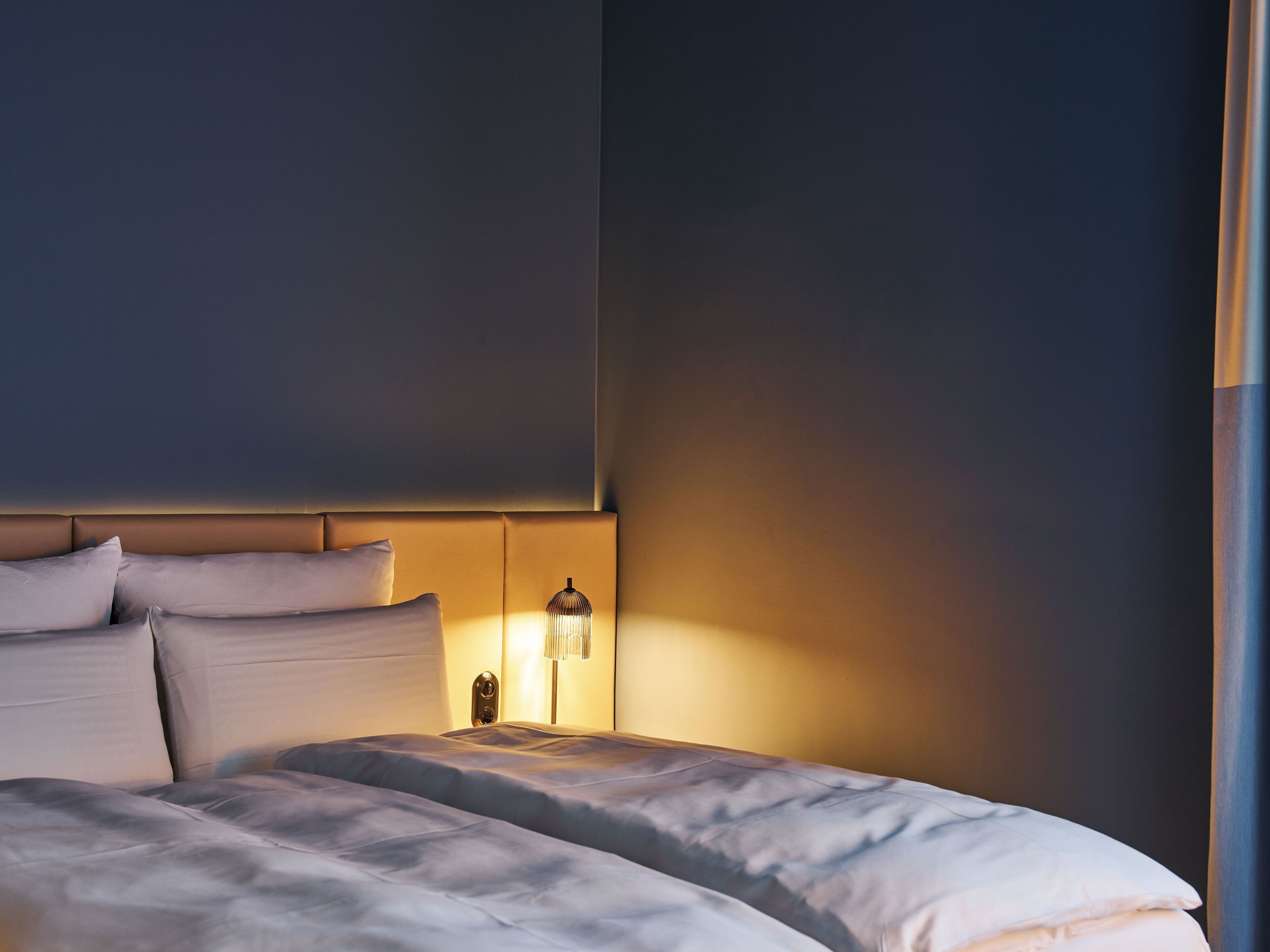 A bedroom with a large bed, a headboard, and a bedside lamp.