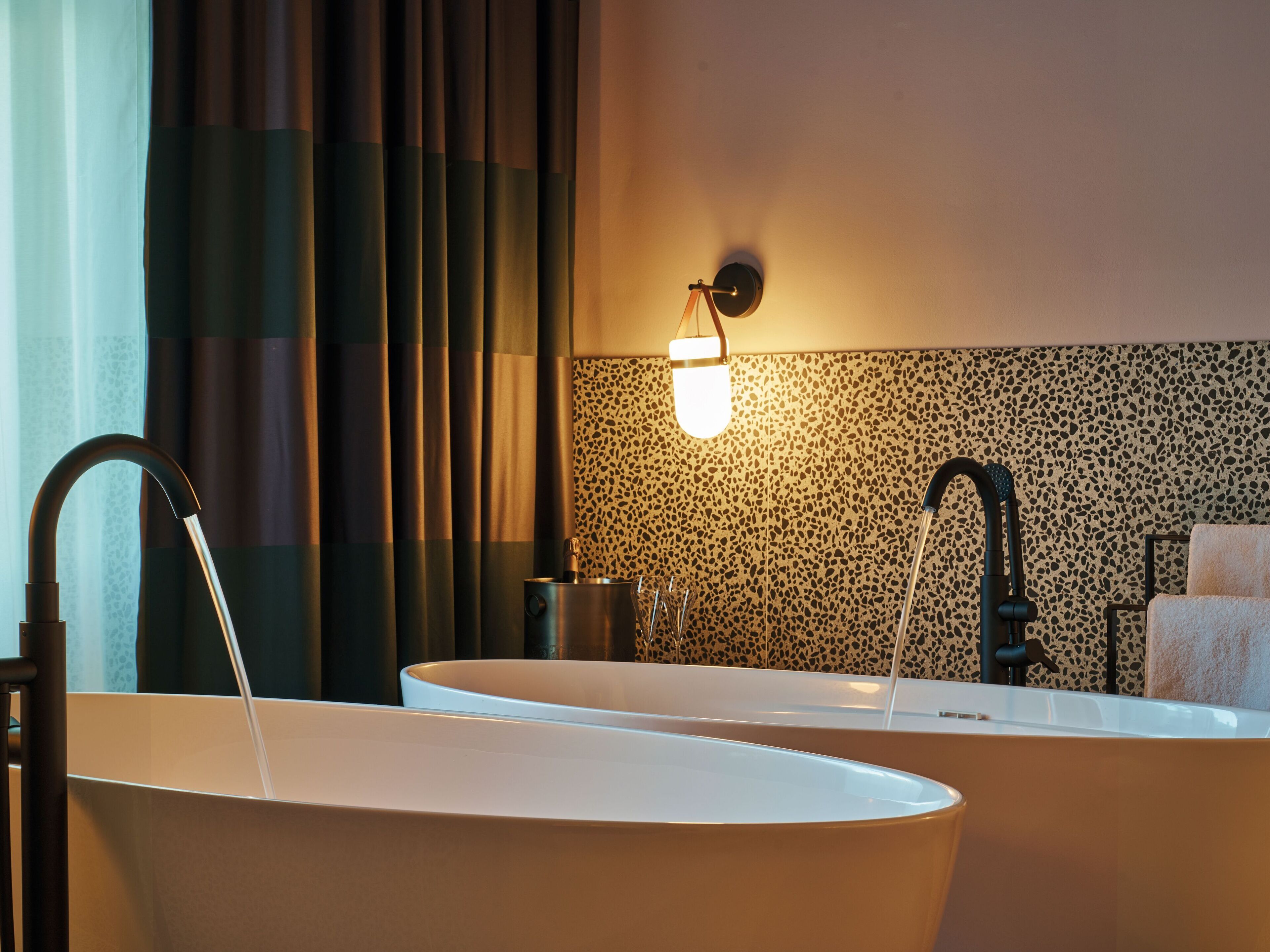 Un bagno con due lavabi, un porta asciugamani e un lampadario a parete.