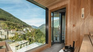 Una habitación moderna con un ventanal grande que ofrece una vista panorámica de un pueblo y montañas.