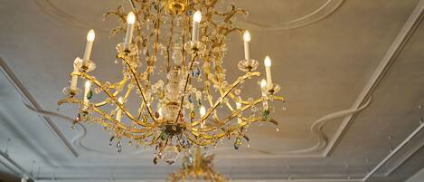 A grand chandelier with multiple candle-like lights and crystal decorations.