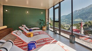 Un moderno salón con ventanales y vistas panorámicas a la montaña, con zona de estar que incluye sillones reclinables y un gran ventanal.