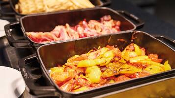 Ein reichhaltiges Buffet mit verschiedenen Speisen, darunter Kartoffeln, Speck und Rührei.