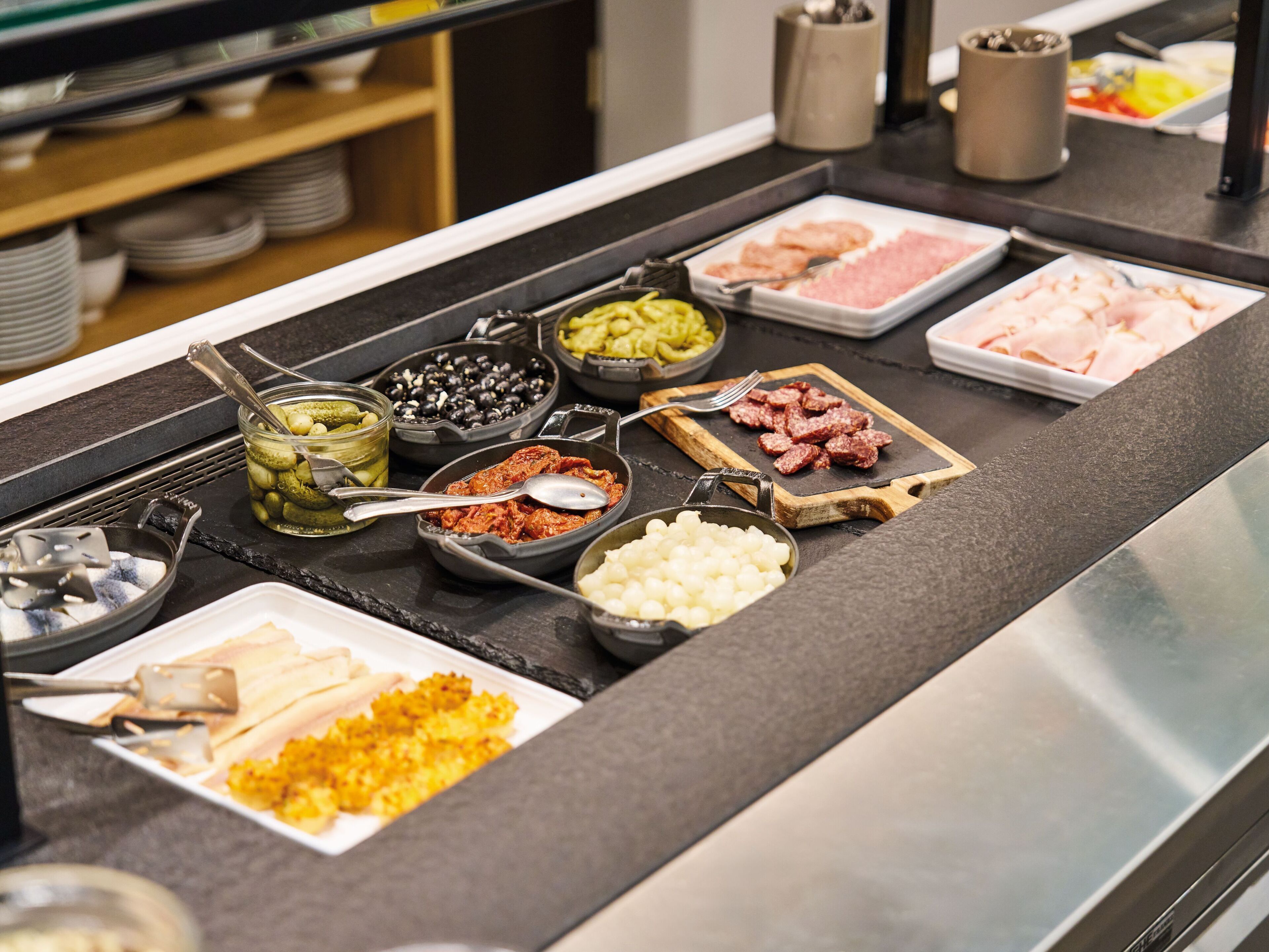 Een buffet met diverse soorten eten, zoals vleeswaren, kazen en sauzen.