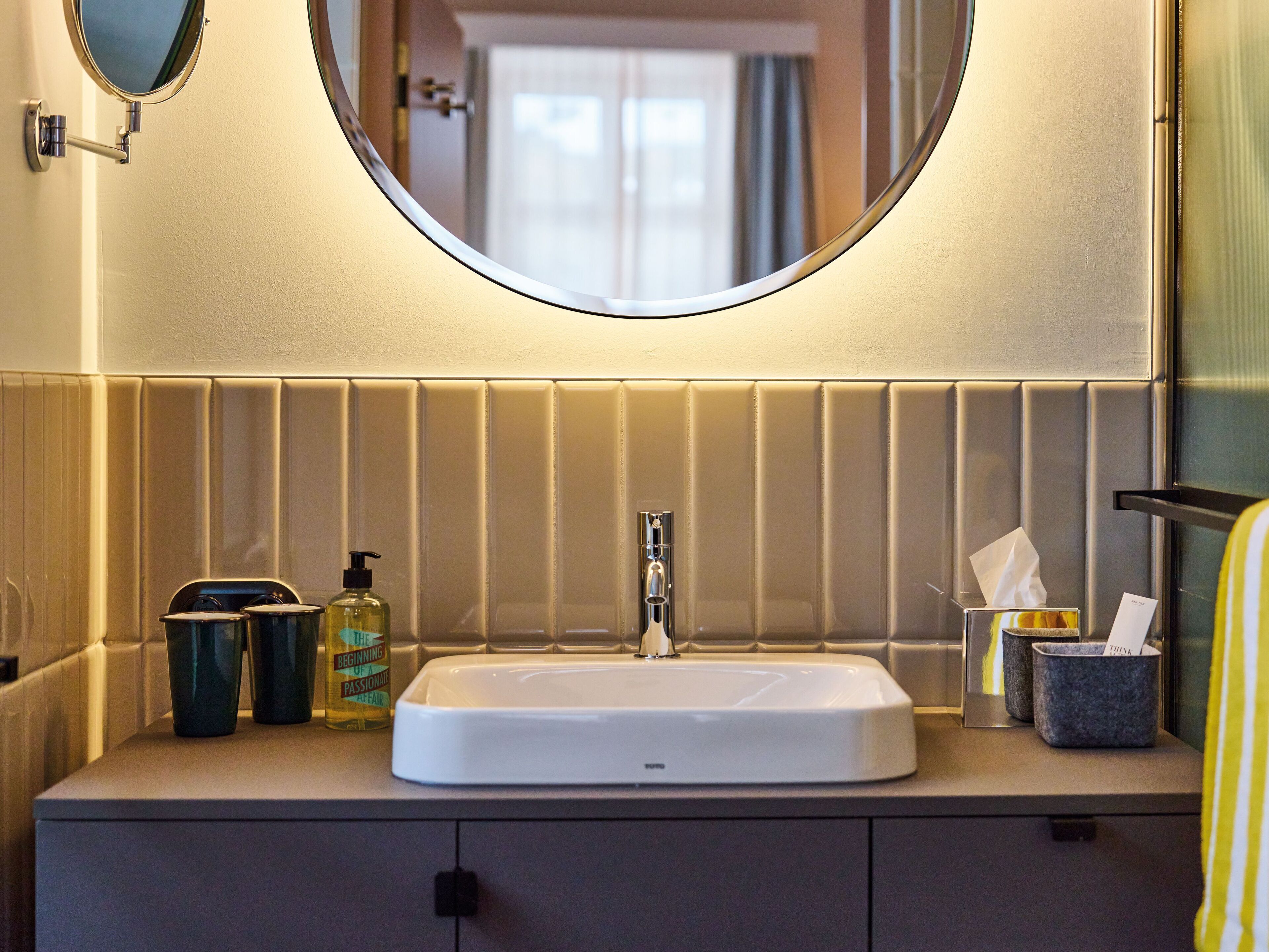 Une salle de bain avec un lavabo blanc, un miroir et un porte-serviettes.