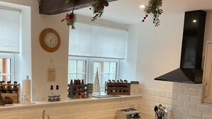 Une cuisine moderne équipée d’un lave-vaisselle encastré, d’un évier et d’un grille-pain. Une guirlande décorative est accrochée au-dessus de l’évier et un petit sapin de Noël est posé sur le rebord de la fenêtre.