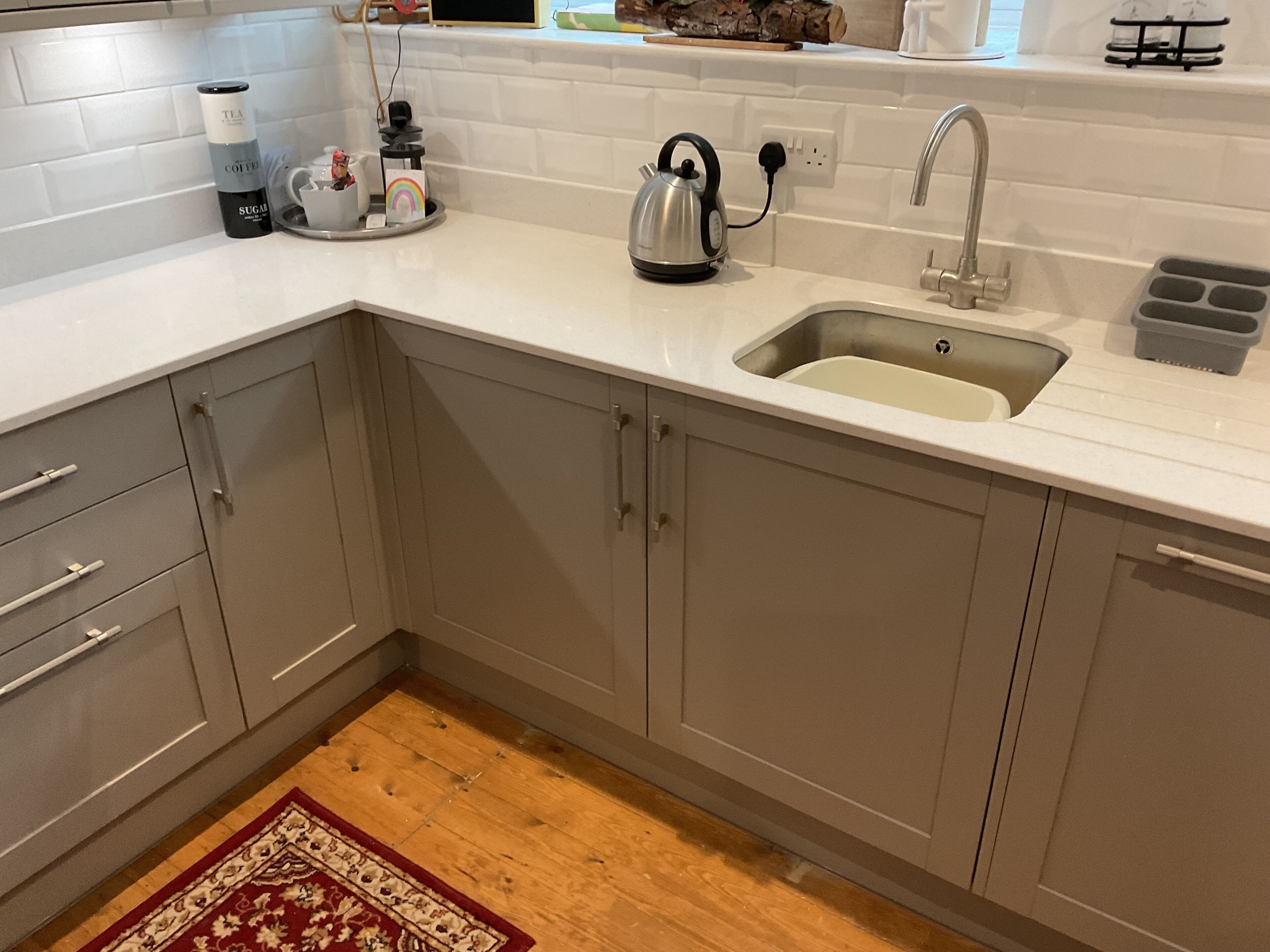 A modern kitchen with a sink, kettle, and coffee maker.