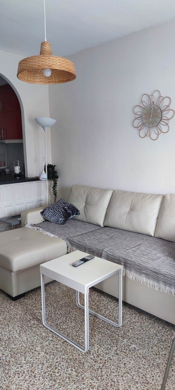 Ein modernes Wohnzimmer mit einer Couch, einem Couchtisch, einer Hängelampe und einer Wanddekoration.