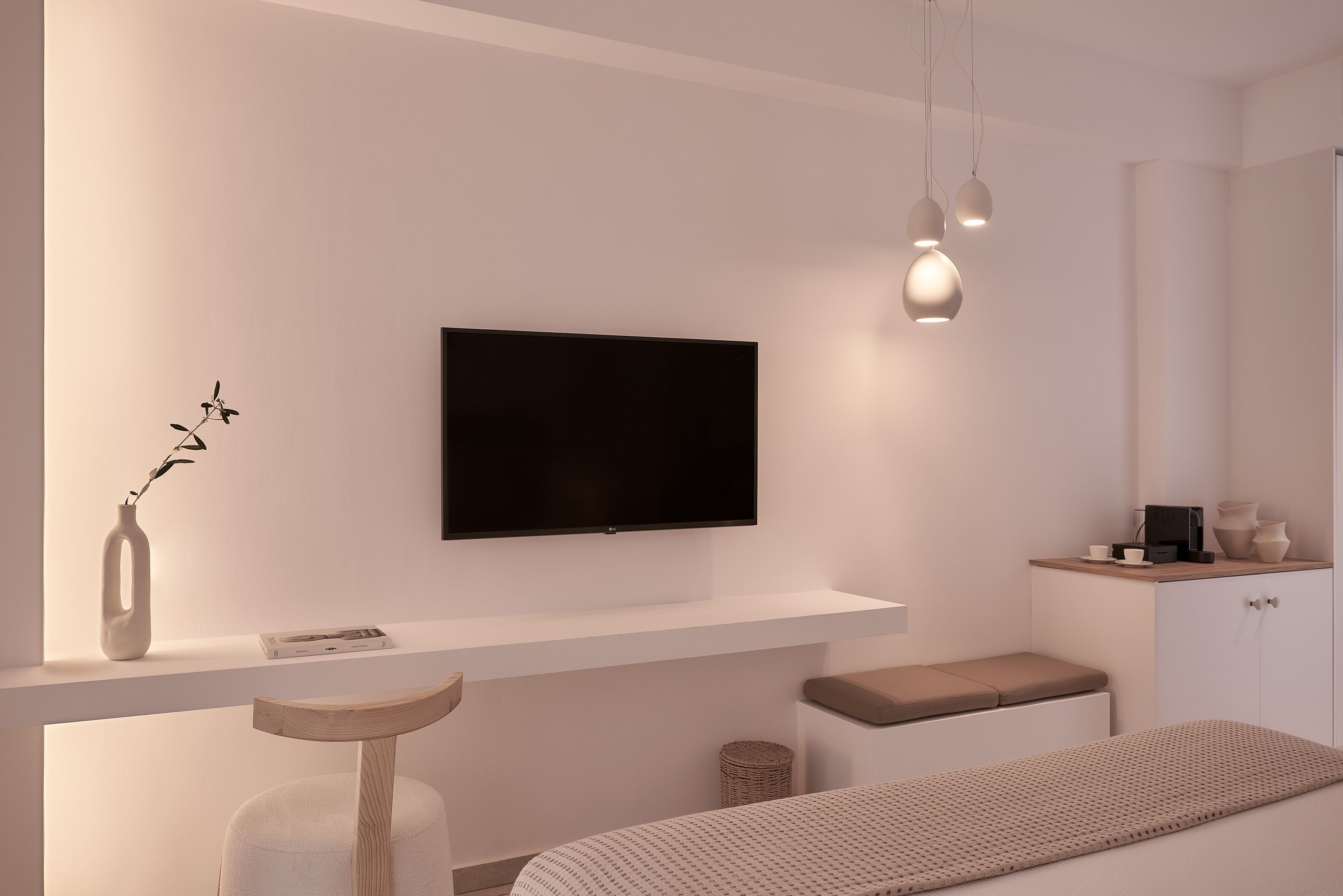 Une chambre à coucher moderne équipée d’un téléviseur à écran plat, d’une table de chevet, d’une chaise, d’un banc et d’une armoire.