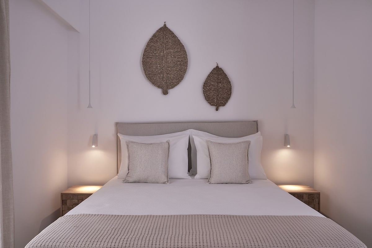 Quarto moderno com uma cama grande, duas luminárias de parede e duas obras de arte na parede.