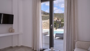 Habitación con televisión en la pared, una mesita con taza y platillo, y vista a una piscina y zona de estar al aire libre a través de un ventanal.
