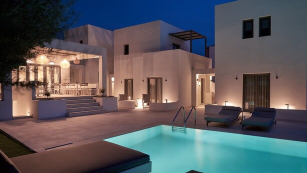 Un área de piscina moderna con sillones de descanso y un bar.