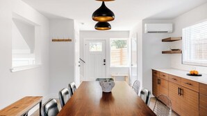 Un espace de salle à manger moderne avec une table en bois, des chaises en métal et un luminaire suspendu original.