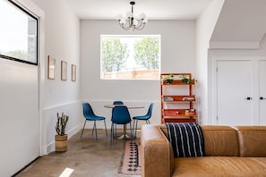 A modern living room with a sofa, a dining table with chairs, a chandelier, and a bookshelf. - 5 Min from Moody - Austin's Eastside Gem (Austin)