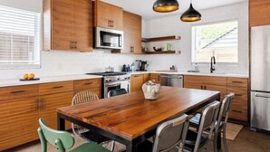 Une cuisine moderne avec des meubles en bois, un réfrigérateur en acier inoxydable et une table à manger avec des chaises.