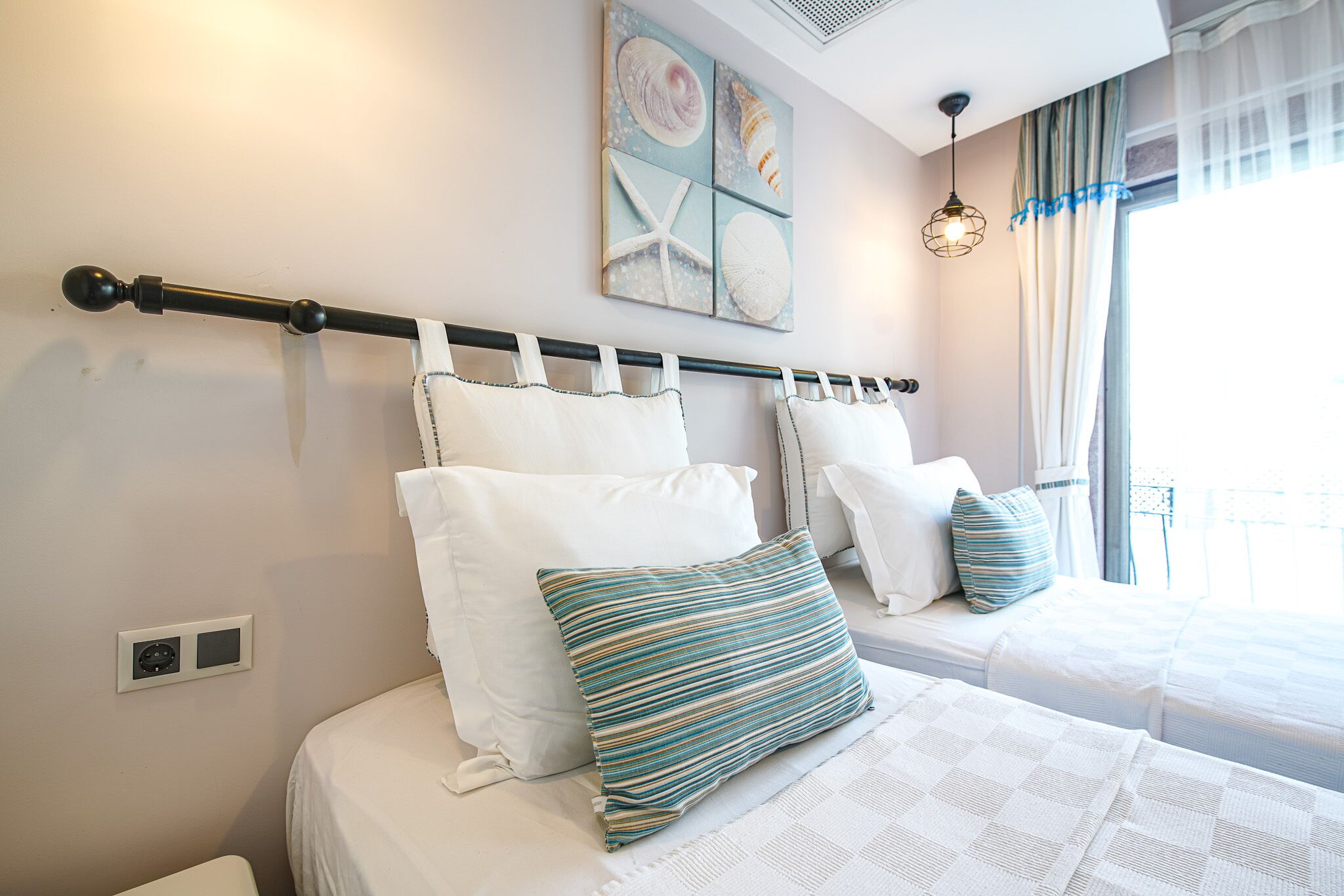 Une chambre avec deux lits, une tête de lit et un luminaire fixé au mur.