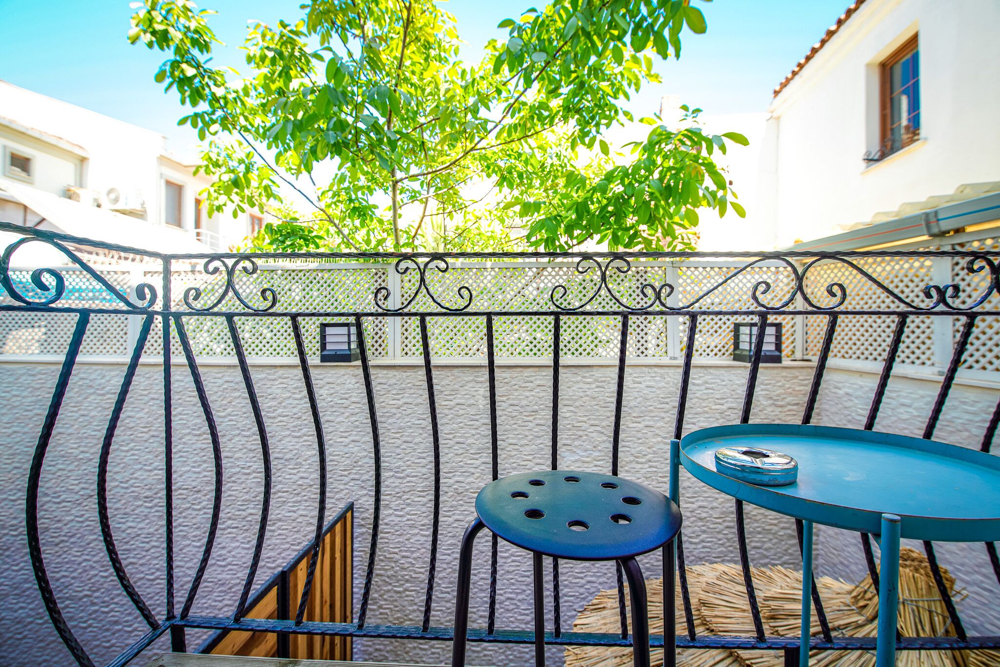 Une terrasse avec une rambarde en métal, une petite table ronde et une chaise.