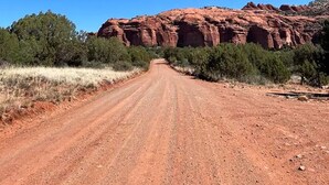 Un chemin de terre menant à une formation rocheuse rouge.
