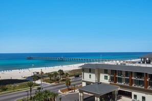 Un hotel frente al mar con vista a la playa, un muelle y un estacionamiento.