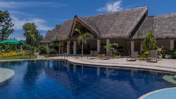 Una piscina al aire libre, sillones reclinables de piscina