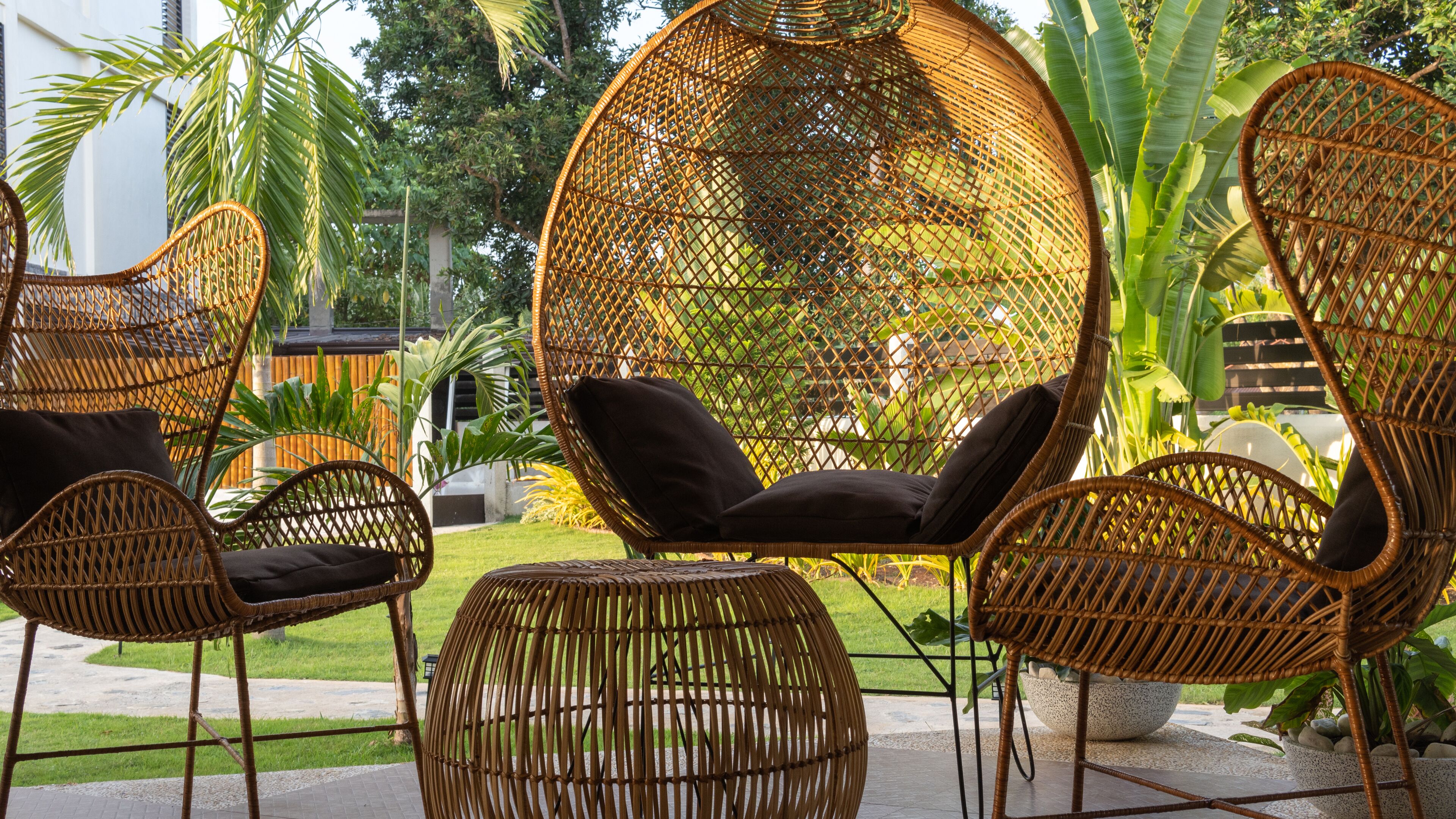 A wicker lounge area with cushioned seating and a large woven canopy.