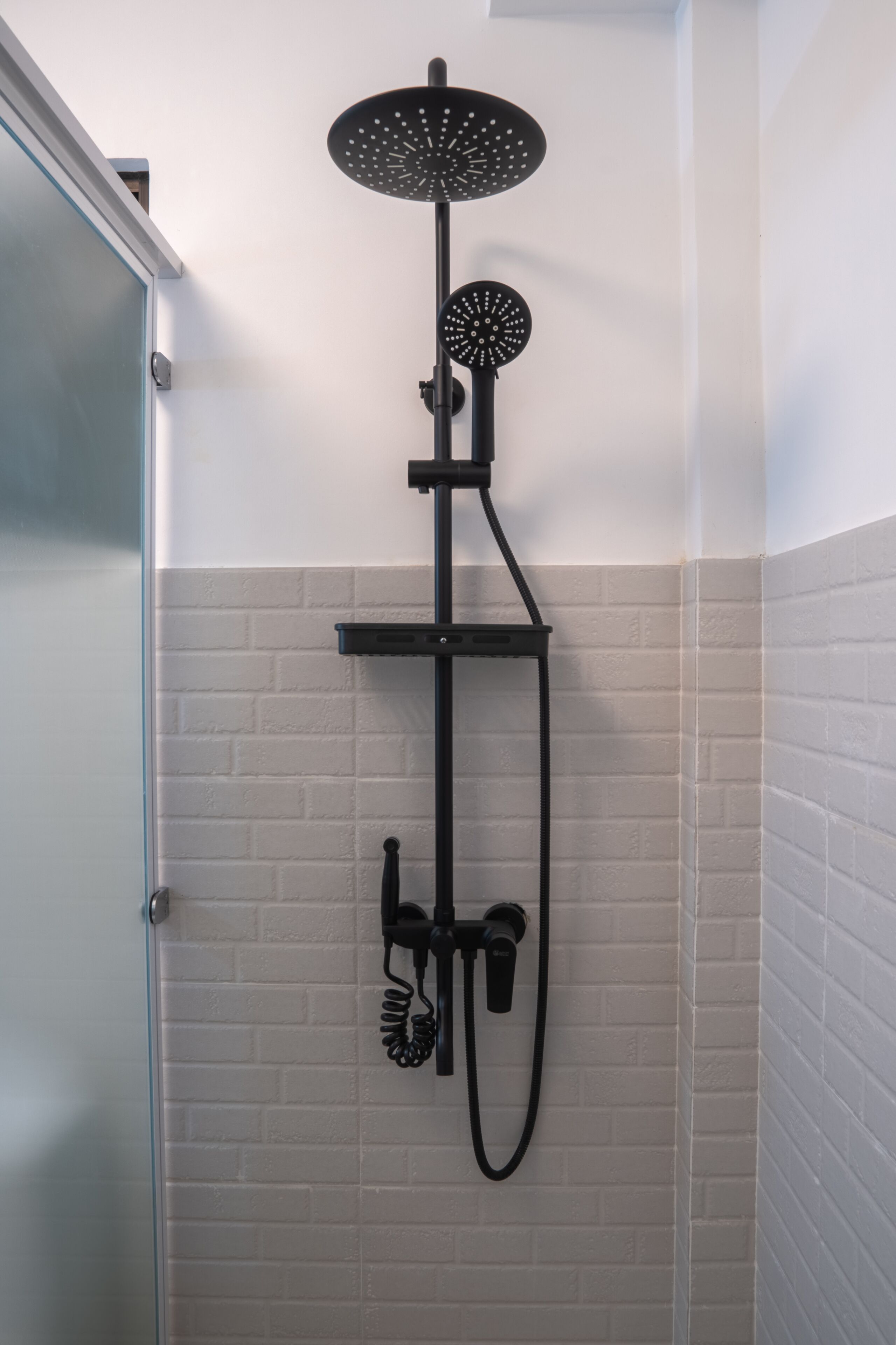 A shower with a rain showerhead and handheld showerhead, mounted on a black metal stand.