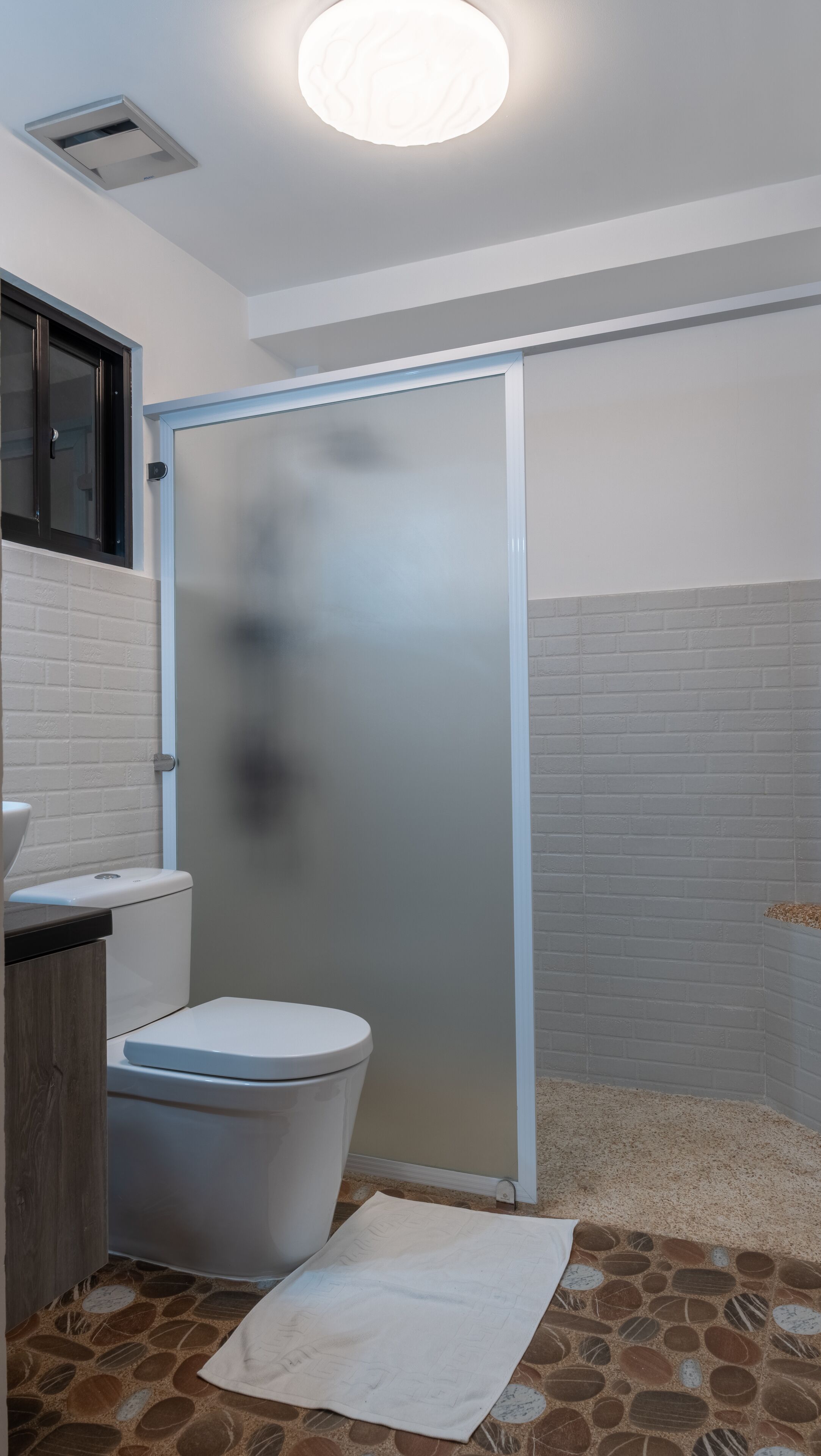 Un baño con inodoro, cabina de ducha y lavabo.
