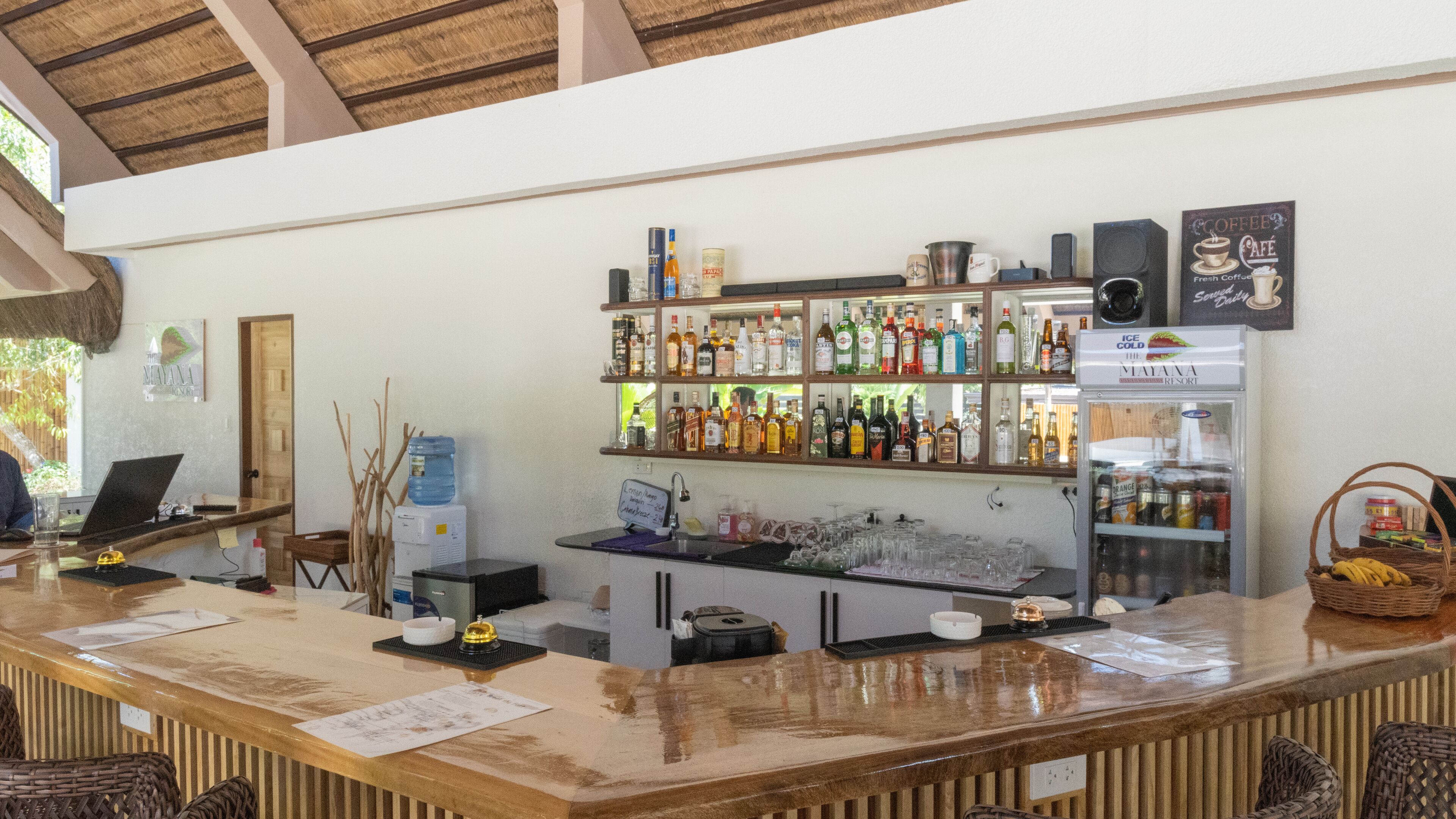 A bar area with a variety of liquor bottles, a water dispenser, and a refrigerator.