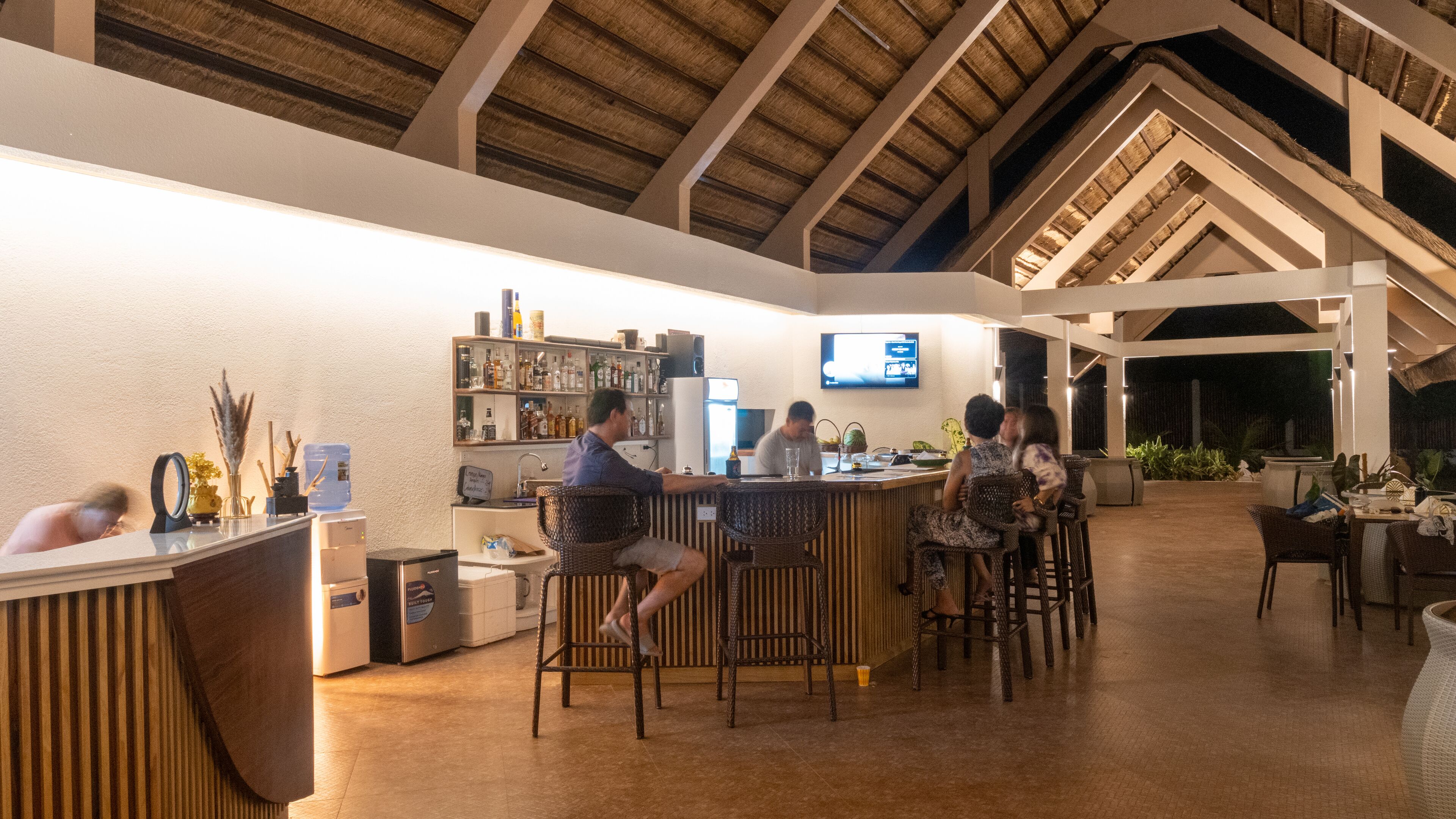 Eine Bar mit hoher Decke und Holzbalken, Barhocker und einer Theke mit einem Barkeeper.