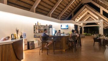 Eine Bar mit hoher Decke und Holzbalken, Barhocker und einer Theke mit einem Barkeeper.