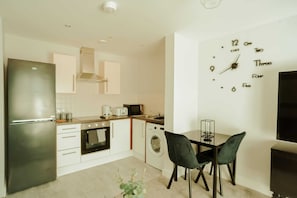 Enjoy meals in the kitchen with an oven, refrigerator, and compact washing machine, and dine at the adjacent table with two chairs.