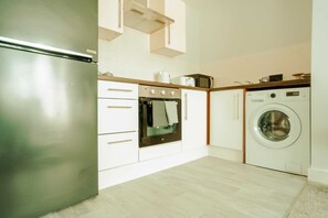 A compact kitchen with a stainless steel refrigerator, a built-in oven, and a front-loading washing machine. - Chic 2 Bedroom Apartment Salford Quays, the Lowry (Salford)