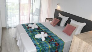 Una habitación de hotel con cama, mesita de noche, una silla y un balcón con vistas.